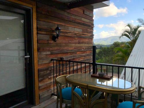 a patio with a table and chairs on a balcony at THE GOLDEN RETREAT POOL HOUSE in Uki