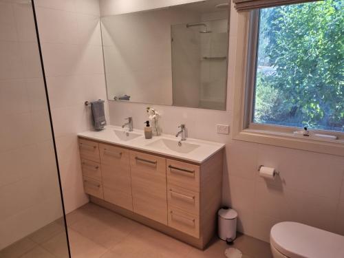 baño con lavabo, espejo y ventana en Donnybrook Cottages - Donnybrook, en Clare