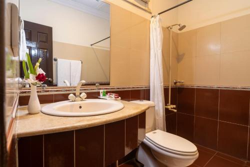 a bathroom with a sink and a toilet and a mirror at Hotel One Lalazar Multan in Multan