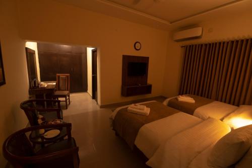 a hotel room with two beds and a desk at Hotel One Lalazar Multan in Multan
