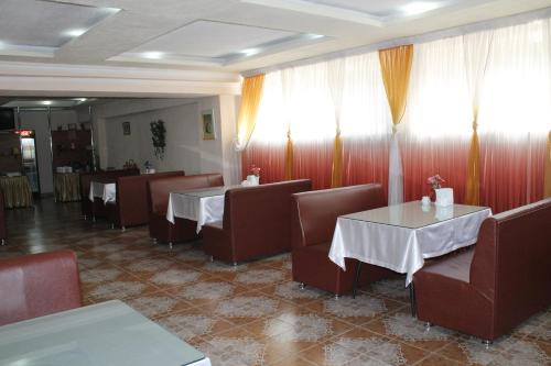 un restaurante con 2 mesas, sillas y cortinas en Green Hotel, en Almaty