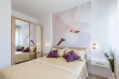 - une chambre avec un lit doté d'oreillers violets et d'un miroir dans l'établissement Apartments Niro, à Split