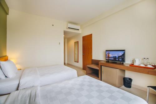 a hotel room with two beds and a flat screen tv at Hotel Luwansa Palangkaraya in Palangkaraya