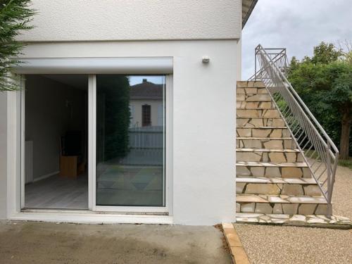 Casa blanca con puerta de cristal y escalera en Chambre aux portes du marais Poitevin, en Aiffres