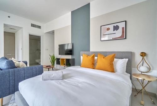 a bedroom with a large white bed with orange pillows at Stella Stays Pristine Studio Dubai JVC Large Terrace in Dubai