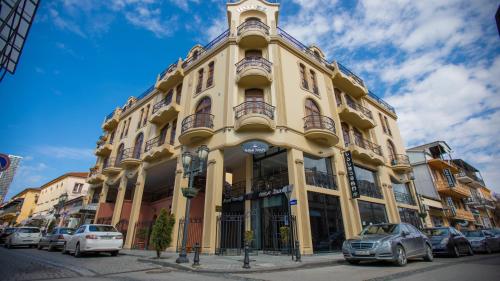 a yellow building with cars parked in front of it at Royal Venezia Hotel in Batumi