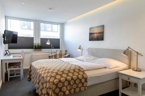 a bedroom with a bed and a desk and a television at acora Kiel Living the City in Kiel