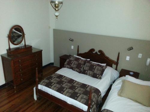 a bedroom with two beds and a dresser and a mirror at New Arapey Hotel in Montevideo