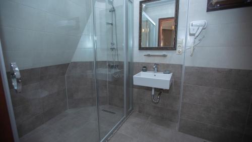 a bathroom with a shower and a sink and a mirror at Royal Venezia Hotel in Batumi