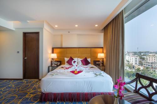 a bedroom with a large bed with a large window at Grand Palace Hotel & Resort Sylhet in Sylhet