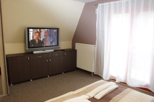 um quarto com uma televisão numa cómoda com uma cama em Chill House em Miskolc