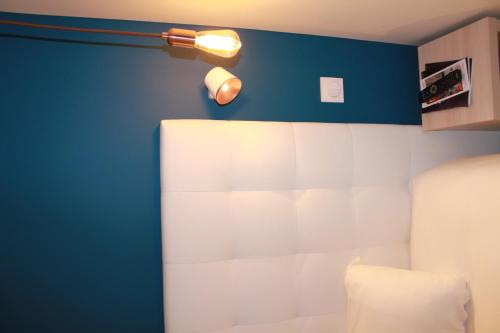 a bedroom with a blue and white wall with a lamp at Hôtel La Fontaine Caen Centre in Caen