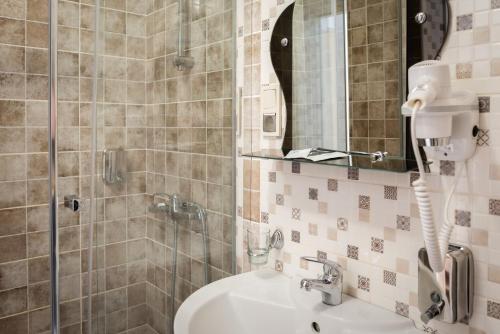 a bathroom with a sink and a shower with a mirror at Priokskaya Hotel in Ryazan