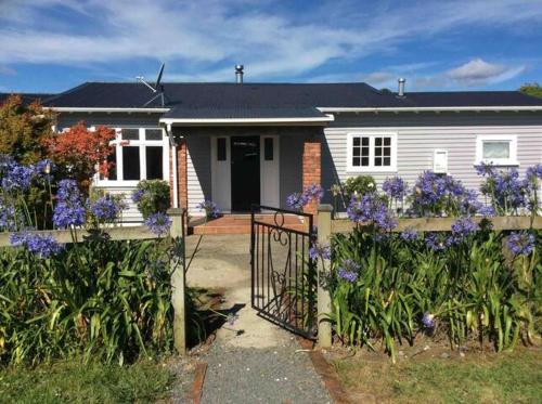 een wit huis met een hek en paarse bloemen bij Rural Country Retreat in New Plymouth