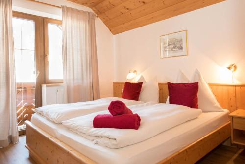 a bedroom with a large white bed with red pillows at Ferienwohnungen Schwalbennest in Mauterndorf