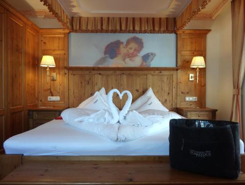 a bed with white sheets and a picture of a couple at ... mein romantisches Hotel Toalstock in Fiss