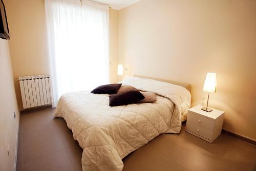 a bedroom with a bed and a lamp and a window at Residence Sole Mare Alaxi Hotels in Alassio
