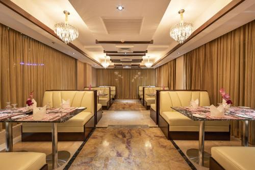 a dining room with tables and chairs and chandeliers at Grand Palace Hotel & Resort Sylhet in Sylhet