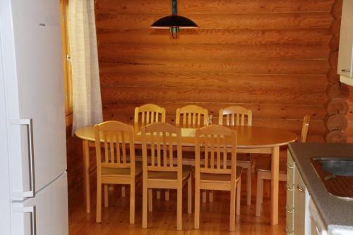 uma cozinha com uma mesa de madeira com cadeiras à volta em Aronsalmen Lomamökit em Nurmes