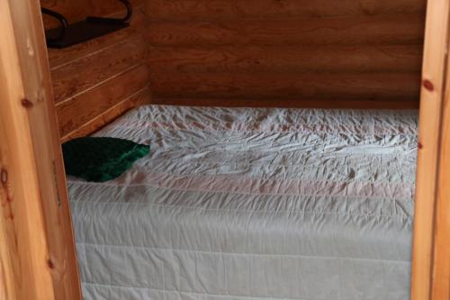 a small bed in a wooden cabin with at Aronsalmen Lomamökit in Nurmes