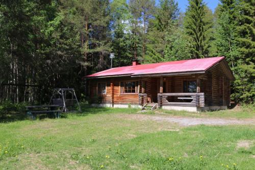 une cabane en rondins avec un toit rouge dans un champ dans l'établissement Aronsalmen Lomamökit, à Nurmes