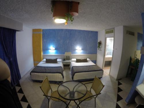 a bedroom with two beds and a table and chairs at Hotel Club del Sol Acapulco by NG Hoteles in Acapulco