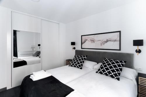 a white bedroom with a bed and a mirror at Housingleón - Five Rooms in León