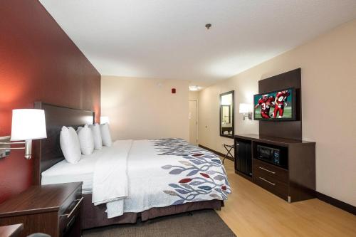 a hotel room with a bed and a flat screen tv at Red Roof Inn & Conference Center Wichita Airport in Wichita