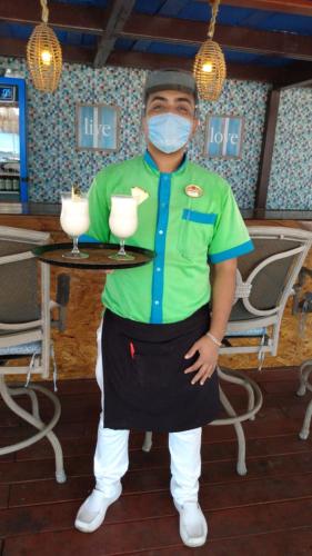 a man wearing a mask holding a table with two drinks at Hotel Club del Sol Acapulco by NG Hoteles in Acapulco