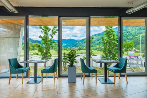 a restaurant with tables and chairs and a view of mountains at Club Hotel am Kreischberg in Sankt Georgen ob Murau