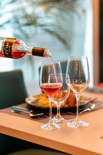 a person pouring wine into two wine glasses on a table at Club Hotel am Kreischberg in Sankt Georgen ob Murau