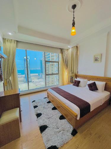 a bedroom with a large bed and a large window at Kiev Tower Hotel Apartments in Manama