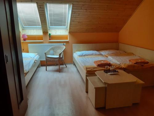 a bedroom with two beds and a table and a chair at Penzion Loučka in Rajhradice