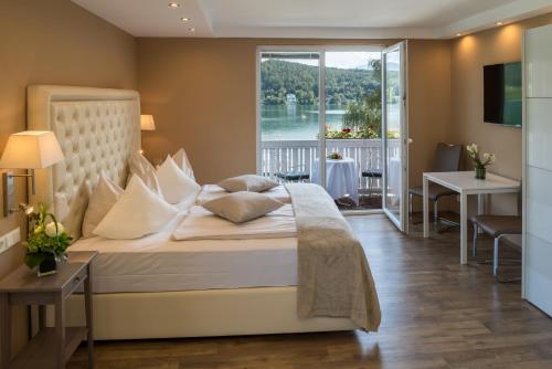 a bedroom with a bed with a large window at Promenaden-Strandhotel Marolt Haupthaus in Sankt Kanzian