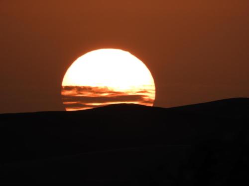 a sunset over the sand dunes in the desert at Sleep In Luxury Tent In Desert in Merzouga