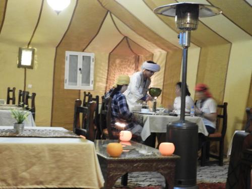 a group of people sitting at tables in a restaurant at Sleep In Luxury Tent In Desert in Merzouga