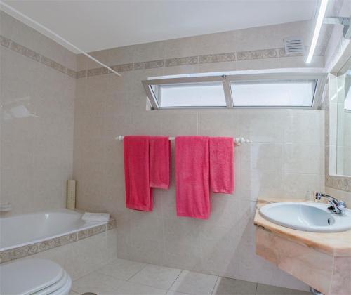 uma casa de banho com toalhas cor-de-rosa, uma banheira e um lavatório. em Quinta Paraiso da Mia - Two bedroom apartment na Praia da Luz