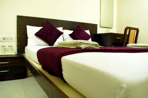 a bedroom with a large bed with purple and white pillows at Sai Sharan Stay Inn- Near MIDC Turbhe Navi Mumbai in Navi Mumbai