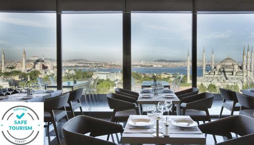een restaurant met tafels en stoelen en uitzicht op de stad bij Hotel Arcadia Blue Istanbul in Istanbul