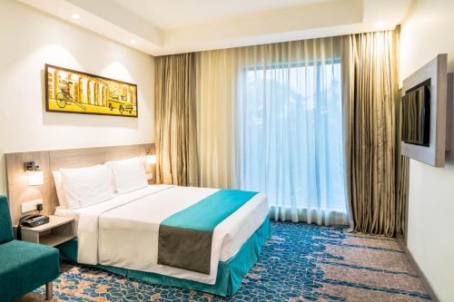 a hotel room with a bed and a window at Holiday Inn Express Kolkata Airport by IHG in Kolkata