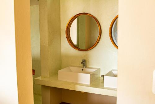 a bathroom with a white sink and a mirror at Tofinho Beach House in Praia do Tofo