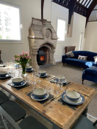 a wooden table with plates and glasses and a fireplace at The old school house in Burwarton