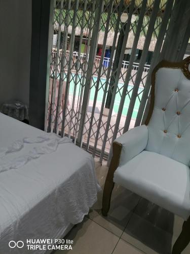 a bedroom with a white chair and a balcony at Lytton Cresent B&B in Pinetown