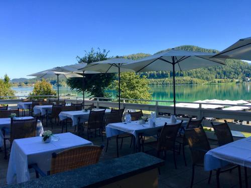 a restaurant with tables and umbrellas and a lake at Hotel Marolt Dependance in Sankt Kanzian