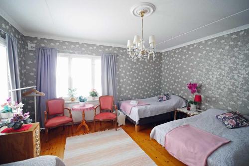 1 dormitorio con 2 camas, sillas y lámpara de araña en Villa Sisu en Överkalix