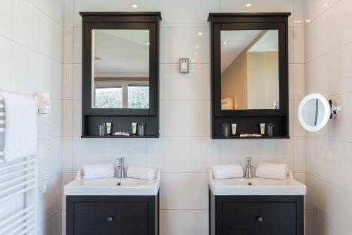 a bathroom with two sinks and two mirrors at Promenaden-Strandhotel Marolt in Sankt Kanzian