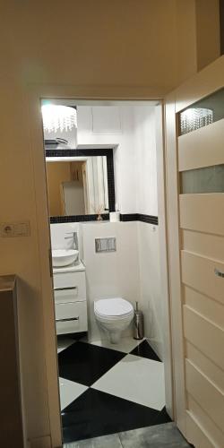 a bathroom with a white toilet and a black and white floor at Apartament Białystok Center in Białystok