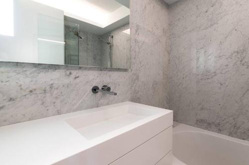 a white bathroom with a sink and a mirror at Liberdade Terrace Apartment in Lisbon