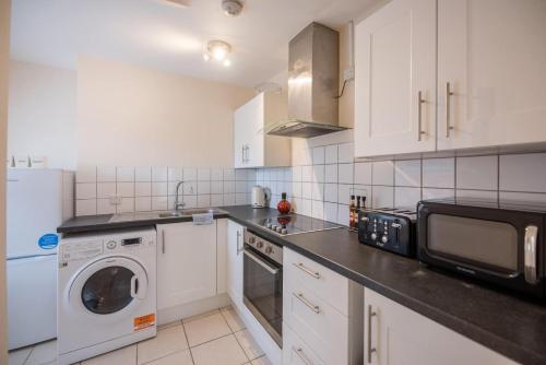 a kitchen with a microwave and a washer and dryer at 2 Abbey Mews, Leiston in Leiston