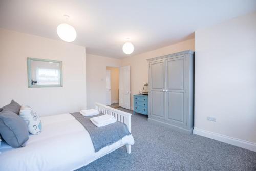 a bedroom with a white bed and a blue cabinet at 2 Abbey Mews, Leiston in Leiston